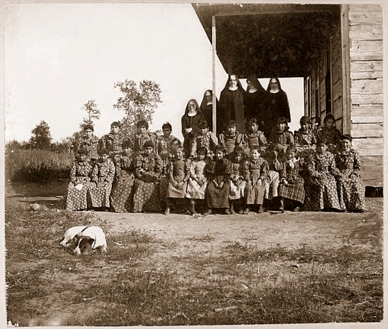 Nuns and students posing in front of St. Mary's mission school on the Red Lake reservation, circa 1889.