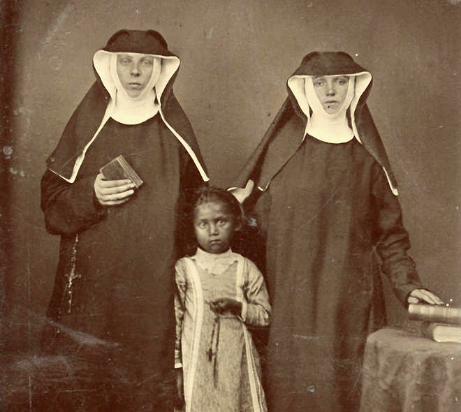 Sisters Lioba Braun and Philomena Ketten posing with an Ojibwe child, circa 1880.