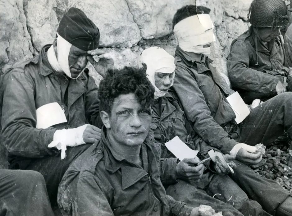 Wounded members of the 16th Infantry Regiment wait for evacuation from the beach on D-Day.